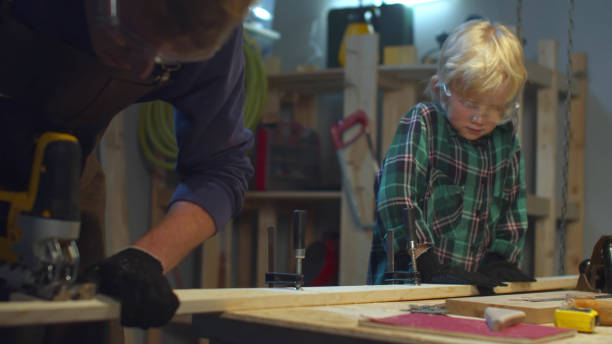 istock The boy helps dad to cut a board. Sliding 1218230372