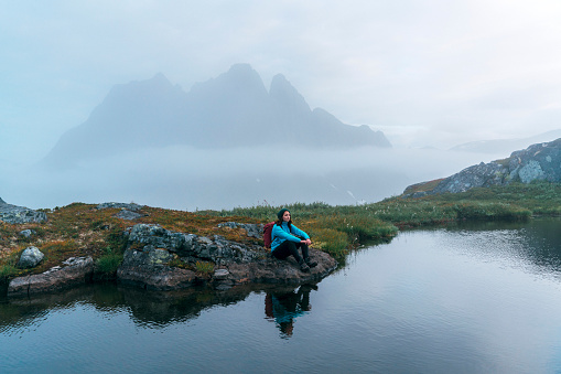 Young Caucasian woman  hiking  in mountains  on Senja mountains in fog