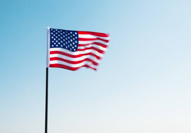 American flag waving against blue sky.
