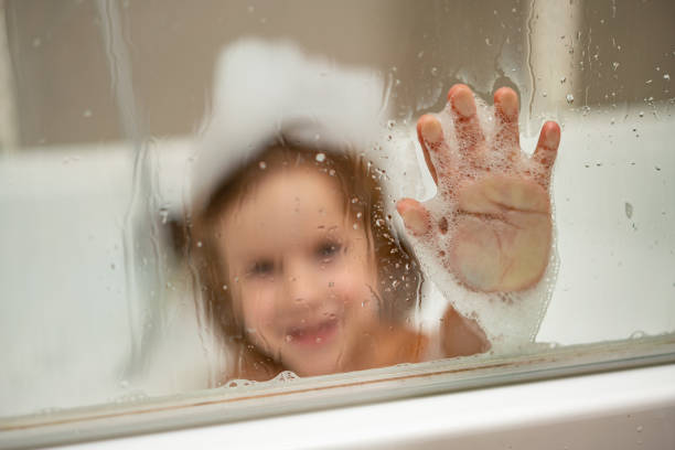 Little boy is behind shower glass and taking a bath