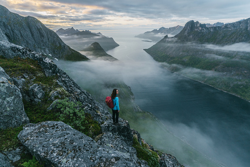 Young Caucasian woman  hiking  in mountains  on Senja island in fog