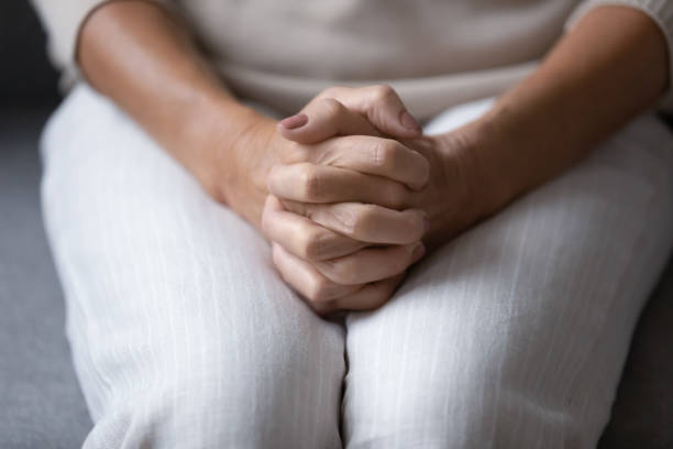 istock Close up wrinkled female hands clasped together on lap. 1218234410