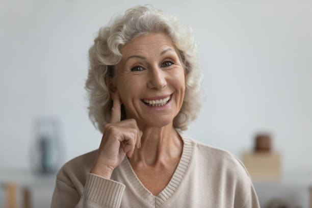istock Smiling senior elderly woman showing on ear. 1218234414