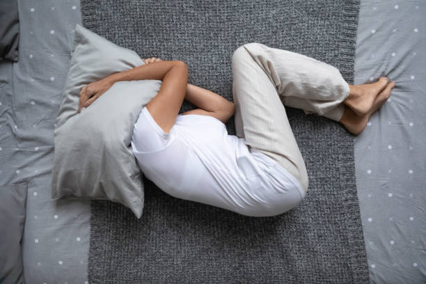 middle aged woman lying on bed, hiding head under pillow. - quilt 60s 70s activity imagens e fotografias de stock