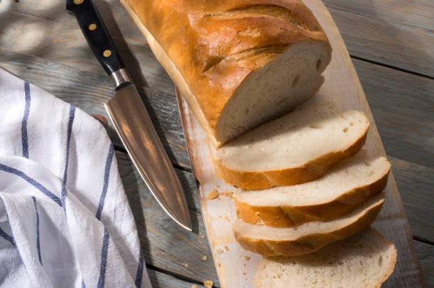 istock Sliced loaf of bread on a cutting board. Top view. Sunlight and fragmented shadow. 1218234532