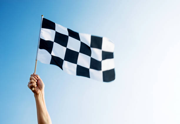 hombre mano sosteniendo la bandera a cuadros en el viento - checkered flag flag auto racing starting line fotografías e imágenes de stock