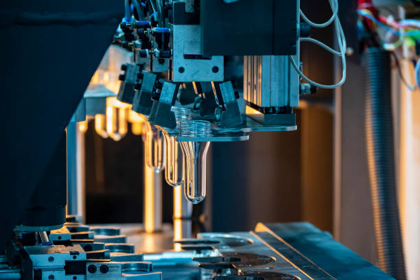 la forma de la preforma del tubo de las botellas precalienta el proceso en la línea de producción a la máquina de soplado automático. - amoldar fotografías e imágenes de stock