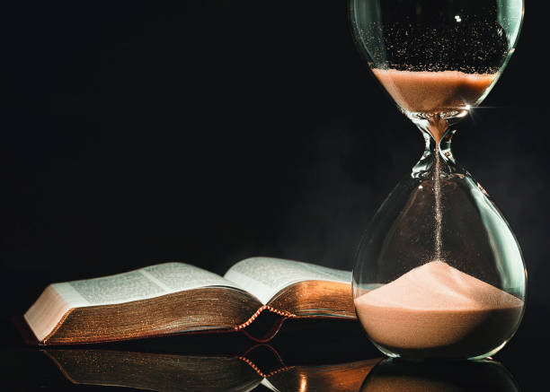 Hourglass and Holy Bible Holy Bible and hourglass representing signs of a coming apocalypse to the world. Armageddon Bible stock pictures, royalty-free photos & images