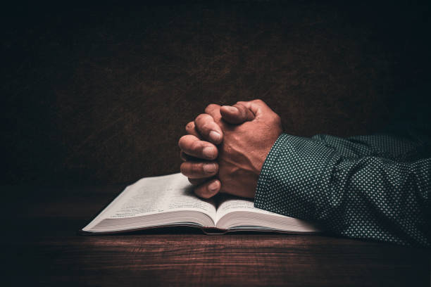 Hands of a man praying over an open bible