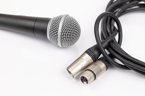 Vocal microphone with xlr mic cable isolated above white background.
