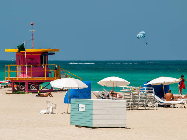Sunny Miami Beach Day Miami Beach, Florida USA. 05/14/2008: Colourful beach scene of vibrant Miami Beach. Lifeguard tower, watersports, and sunbathers can be seen. miami parachuting stock pictures, royalty-free photos & images