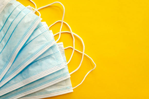istock Surgical disposable face masks on yellow background with copy space 1218238358