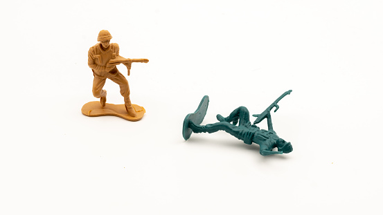 Toy soldier with a radio and a group of fighting soldiers.  The soldiers are in various fighting postures and holding various weapons while ready to engage in battle.