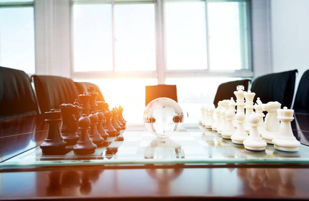 istock Chess pieces and glass earth globe on the conference table 1218241597