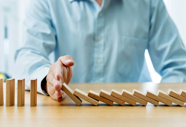 istock Businessman hand stopping falling blocks on table 1218242403