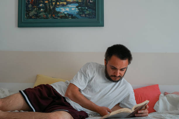 istock Young man reading book in bed 1218245447