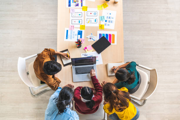 a equipe criativa de negócios da young asian trabalha em conjunto usando computador portátil, projeto de design de software de aplicação móvel. reunião de brainstorming, tecnologia de internet, conceito de trabalho em equipe de colegas de escritório - conference table business meeting business directly above - fotografias e filmes do acervo