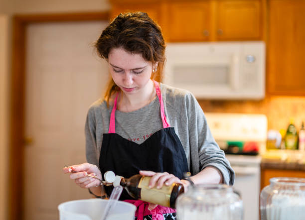 istock Young woman baking banana bread in her home kitchen, adding vanilla extract to the batter. 1218249387