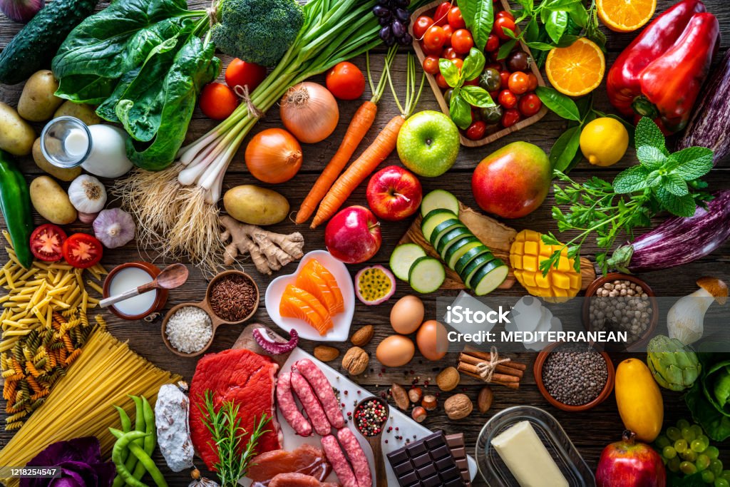Varied food carbohydrates protein vegetables fruits dairy legumes on wood Food and drink large arrangement with carbohydrates protein vegetables and fruits legumes and dairy products on rustic board table Food Stock Photo