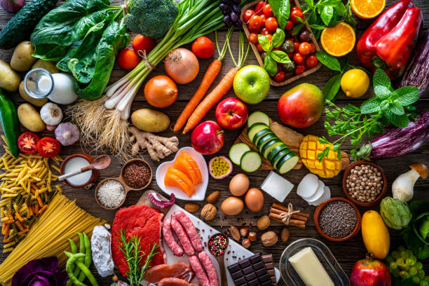 Varied food carbohydrates protein vegetables fruits dairy legumes on wood Food and drink large arrangement with carbohydrates protein vegetables and fruits legumes and dairy products on rustic board table dairy product photos stock pictures, royalty-free photos & images