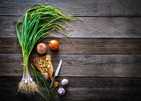 Tender young garlic bunch fresh after harvest on rustic wooden board and cutting board knife with onion and garlics