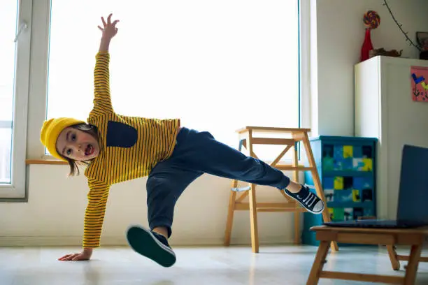 Photo of Little boy dancing break at home. Home Pleasures. Handstand