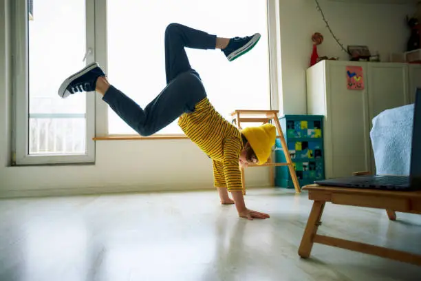 Photo of Little boy dancing break at home. Home Pleasures. Handstand