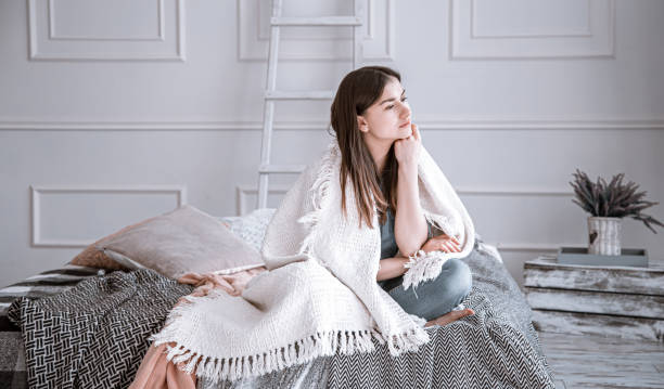 istock A young, thoughtful woman is sitting on the bed . 1218257073