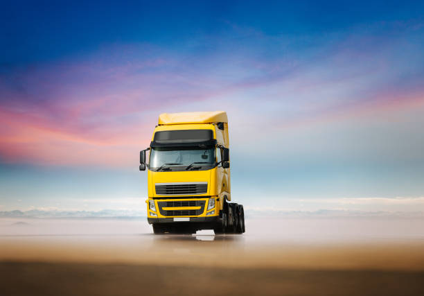 big yellow dump truck is running on the sea coast. a truck carries stones along a sandy beach
