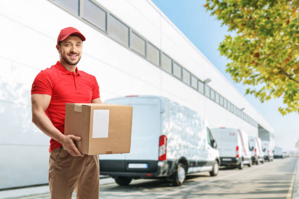 istock Delivery guy holding a package in front of a warehouse 1218259698