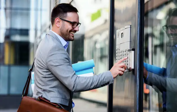 Businessman pushing the button and talking on the intercom in front of the firm