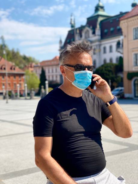 istock Adult man wearing protective mask and using phone 1218261805