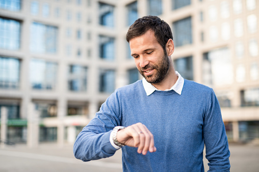 Portrait of casual mid adult man looking at watch and checking time.