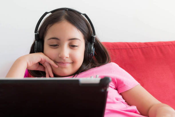 istock child watching videos by tablet lying on the couch 1218267053
