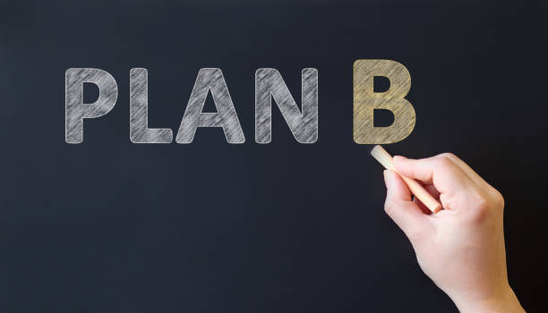 istock PLAN B - text inscription on a black board. Hand with chalk writes text 1218267964