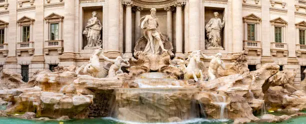 Trevi district, Rome, Italy. Sculptures on Palazzo Poli, a palace building, and on Trevi Fountain, in front, the largest baroque water fountain in the city. Popular tourist/ sightseeing attraction.