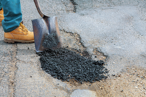 Laying new asphalt, covering the pit, very bad quality road with hole in asphalt