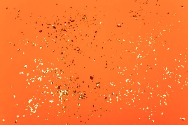 Golden flying sparkles on bright orange background.