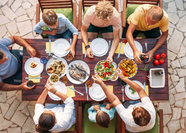 istock Big multigenerational family dinner in process. Top view image on table with food and hands. Food consumption and multigenerational family concept image. 1218285129