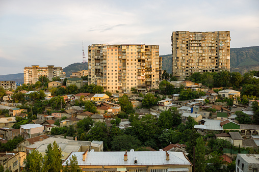 Tbilisi, Georgia - July 25, 2015: A sunset view of Tbilisi showing the large old Soviet Bloc era apartment buildings and mountains in the background.