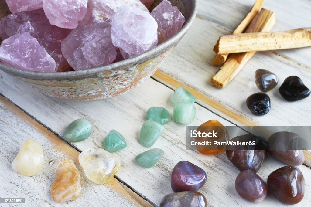Rose Quartz Crystals A top view image of rose quartz crystals with green aventurine, smokey quartz and palo santo smudge sticks on a white wooden table. Crystal Stock Photo