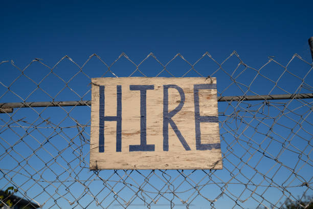 istock 'Hire' sign on  fence with blue sky. 1218292389