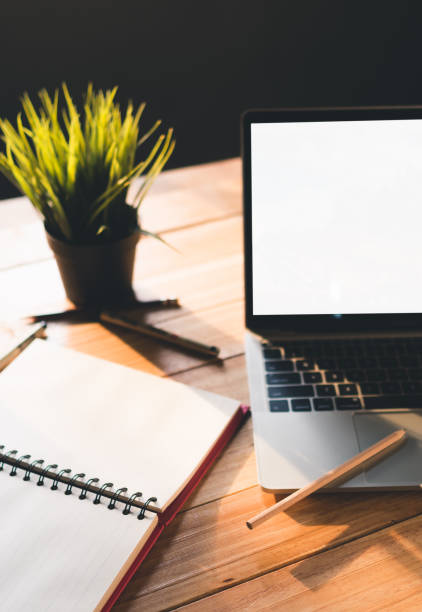 istock white screen laptop on table with empty notebook page, pencil, pens and grass pot 1218295586