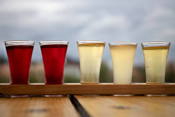 sampler flight tray of apple cider alcohol drinks on a wood table outdoors - hard drink imagens e fotografias de stock