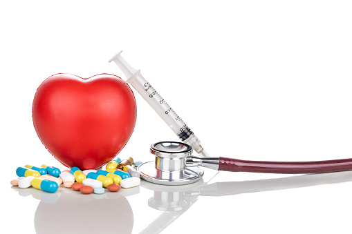 Healthcare concept with medicine pills, caplet, tablet, capsule and red heart, stethoscope, syringe as prop on white background
