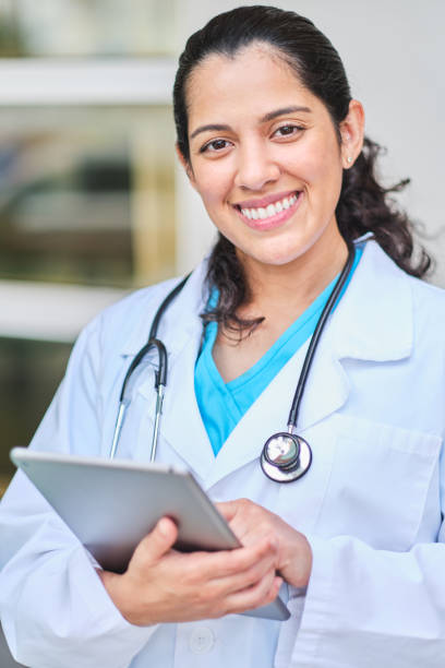 istock Young latin nurse with stethoscope holding a tablet mobile device 1218307495