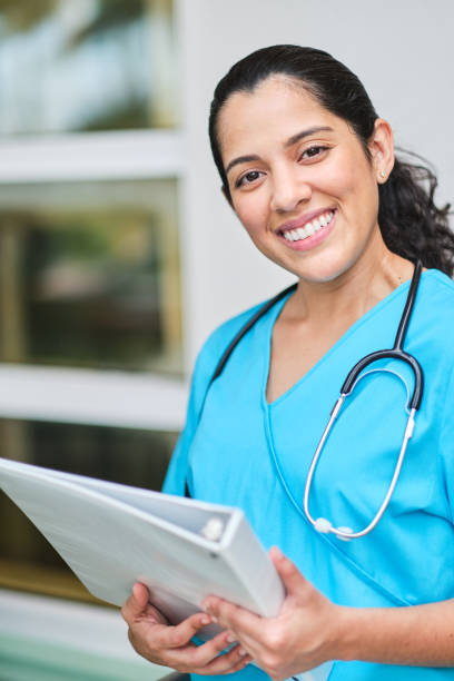 istock Young latin nurse with stethoscope holding a binder clip 1218307608