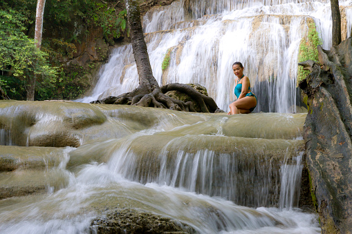 Traveler with blue swimsuit happy at Erawan Waterfall and natural in Kanchanaburi province Thailand. Erawan Waterfall Is a beautiful and famous water fall.