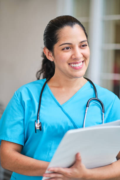 istock Young latin nurse with stethoscope holding a binder clip 1218307817