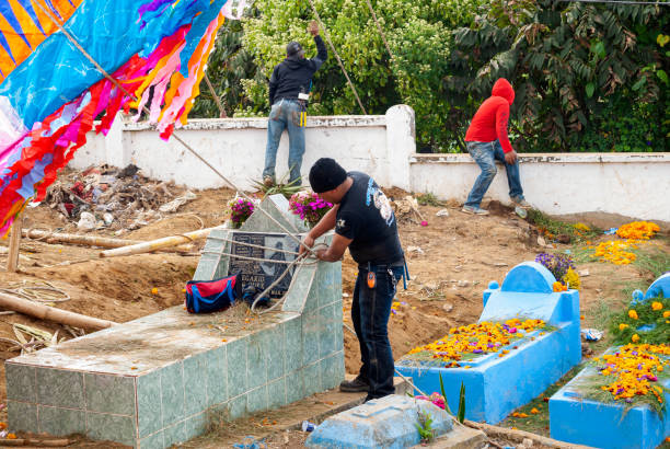 Group of men making giant kite in the cemetery to celebrate the day of the dead. 10/31/17, Santiago Sacatepequez, Guatemala - Group of men making giant kite in the cemetery to celebrate the day of the dead. all hallows by the tower stock pictures, royalty-free photos & images